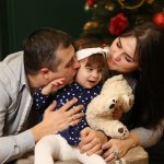 a man and a woman holding a baby and a teddy bear